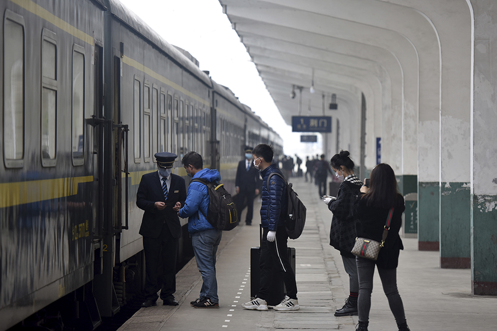 In this photo released by Xinhua News Agency, passengers board a train at the Jingmen Railway Station in Jingmen, central China's Hubei Province, March 25, 2020. Trains carrying factory employees back to work after two months in locked-down cities rolled out of Hubei province, the center of China's virus outbreak, as the government on Wednesday began lifting the last of the controls that confined tens of millions of people to their homes. (Peng Qi/Xinhua via AP)