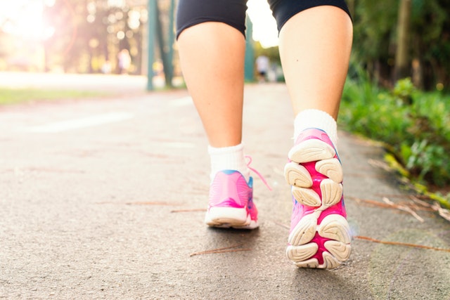 photo of woman wearing pink sports shoes walking 1556710