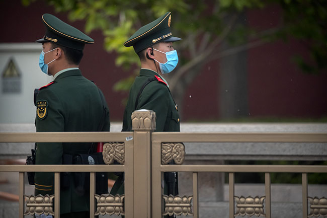 Chinese paramilitary police wearing face masks to prevent the spread of the new coronavirus stand guard along a street near Tiananmen Square in Beijing, Wednesday, April 29, 2020. China, in a step toward returning to business as normal, announced Wednesday that its previously postponed national legislature session would be held in late May. (AP Photo/Mark Schiefelbein)