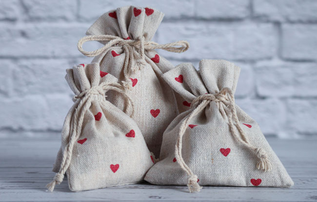 Textile bags with gifts. red hearts are depicted on the fabric. Valentine's Day gift. Close-up of items on a white brick background.