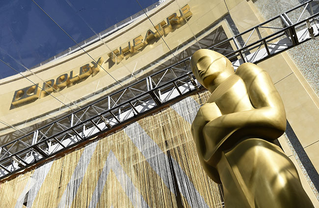 FILE - An Oscar statue is pictured underneath the entrance to the Dolby Theatre on Feb. 24, 2016, in Los Angeles. The Oscars will be held on Sunday, March 27 at the Dolby Theatre in Los Angeles. The ceremony is set to begin at 8 p.m. ET and will be broadcast live on ABC. (Photo by Chris Pizzello/Invision/AP, File)